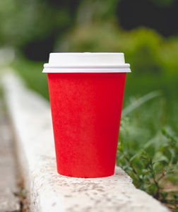 This image is a photo of a red and white plastic cup on gray concrete curb.