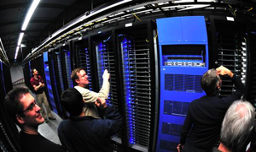 Six people standing and looking at a data storage unit inside of Facebook data storage site.