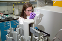 Woman laboratory technician looking into a biotechnology system